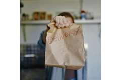 Person holding food delivery paper bag.